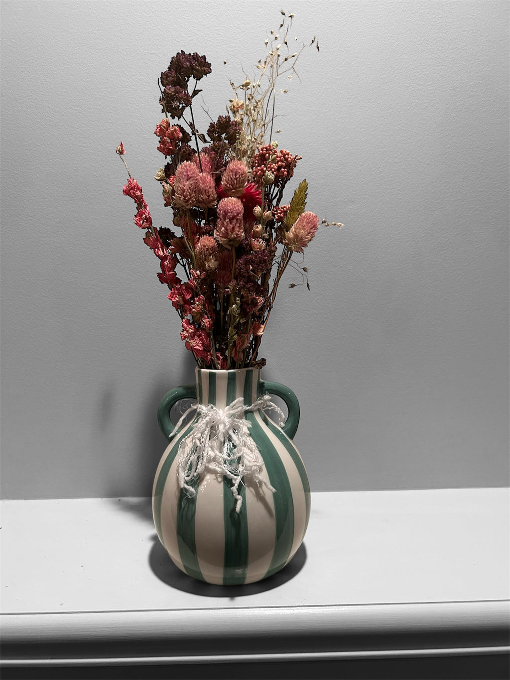 Green striped vase with dried floral arrangement