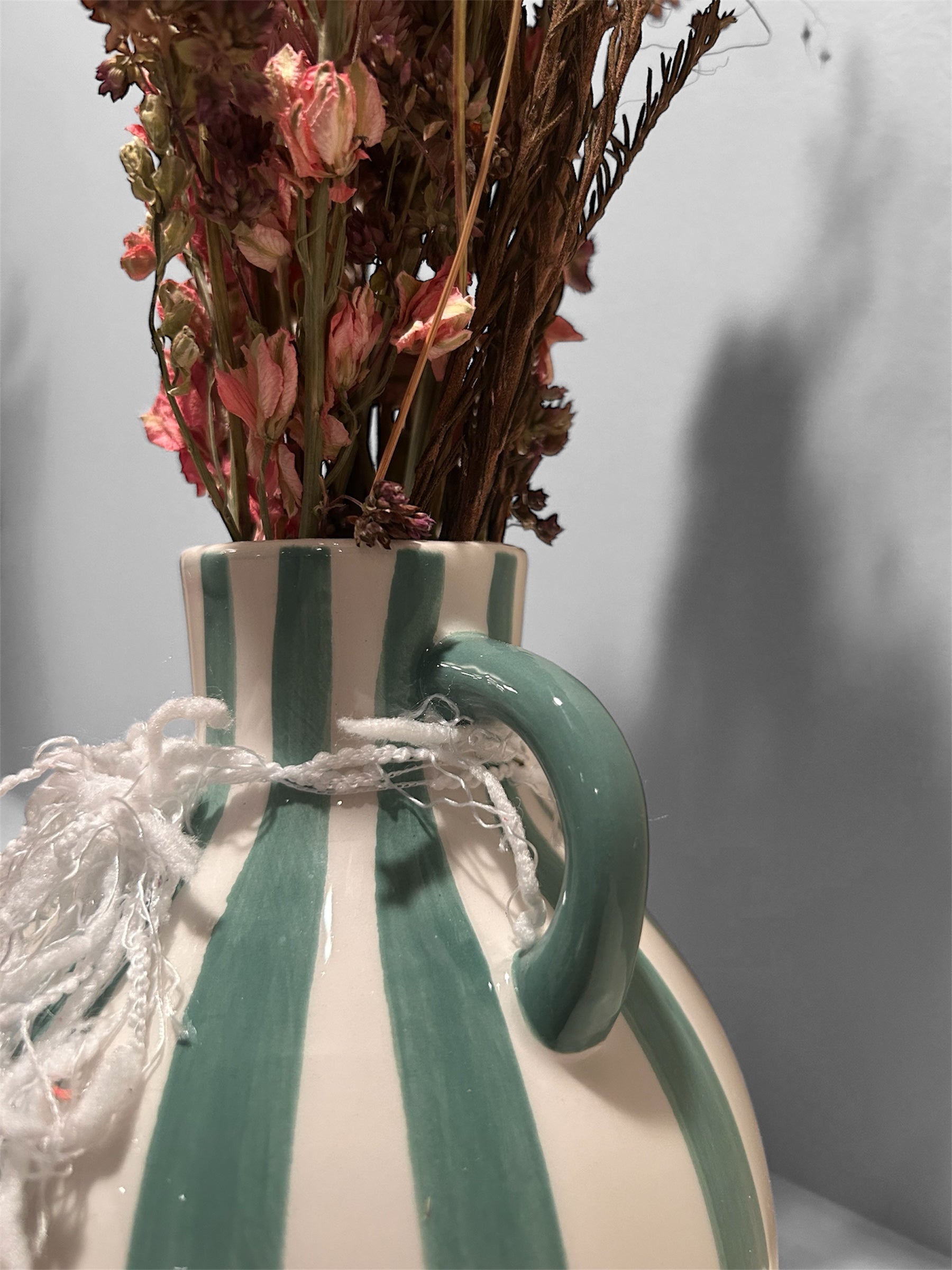 Green striped vase with dried floral arrangement