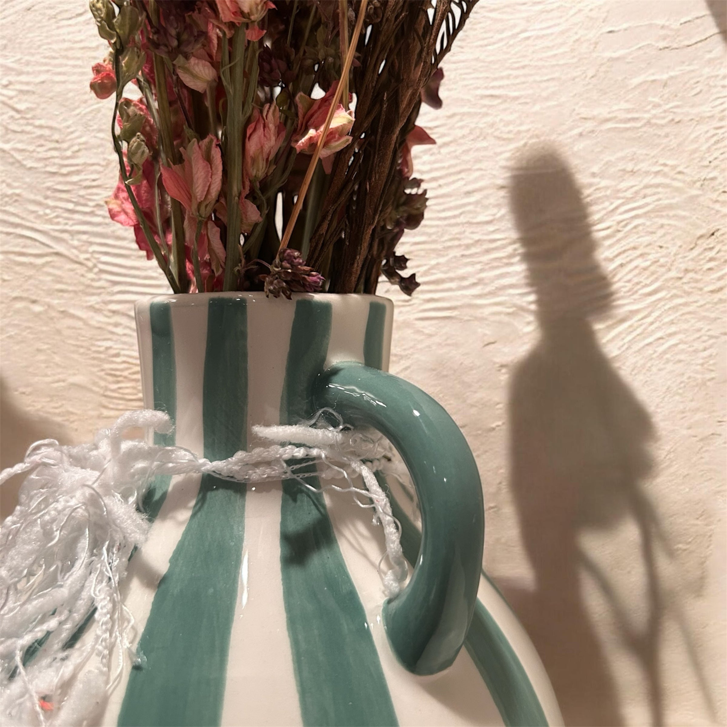 Green striped vase with dried floral arrangement
