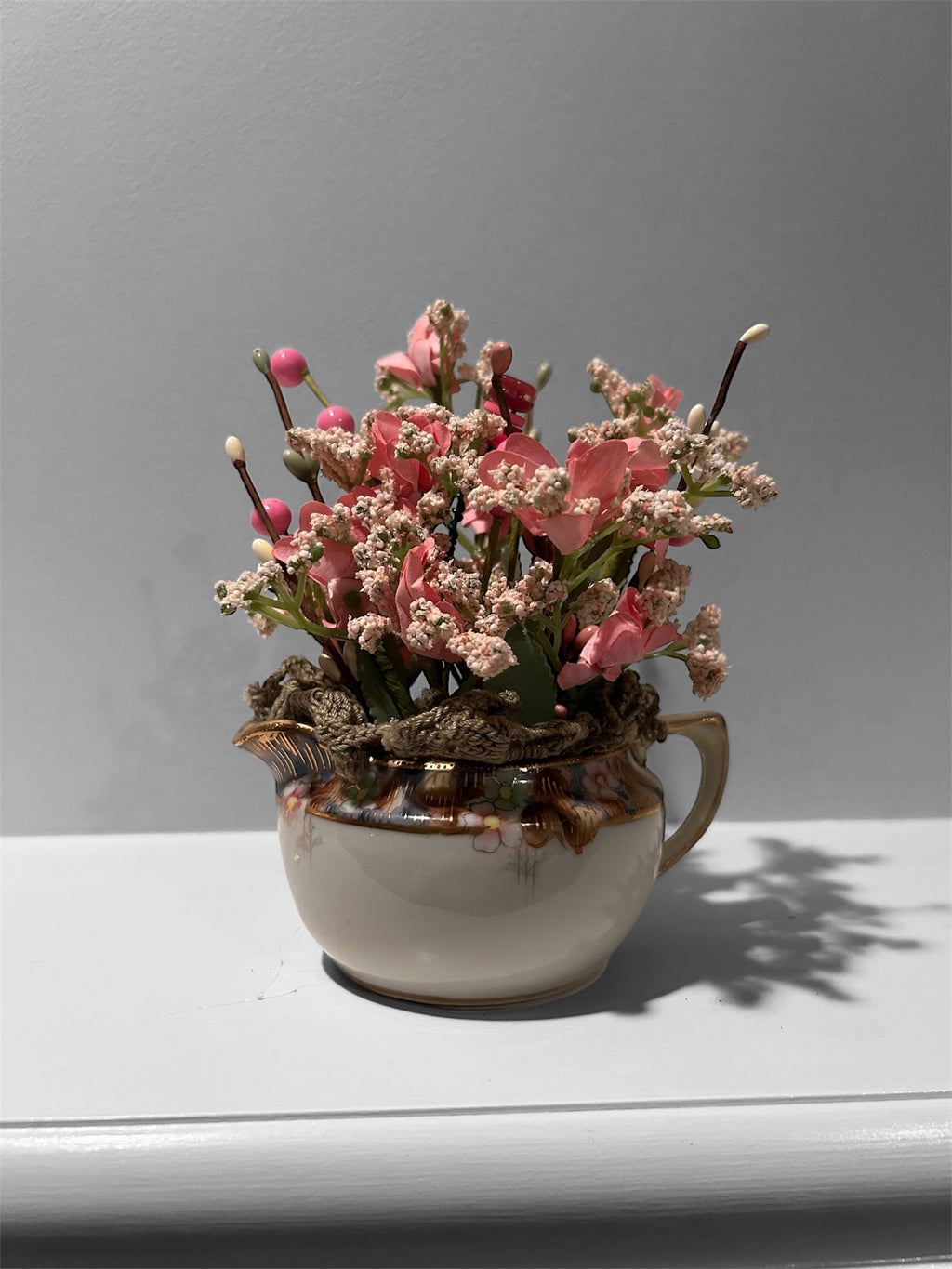 Pink flowers in white/gold creamer arrangement - green doily