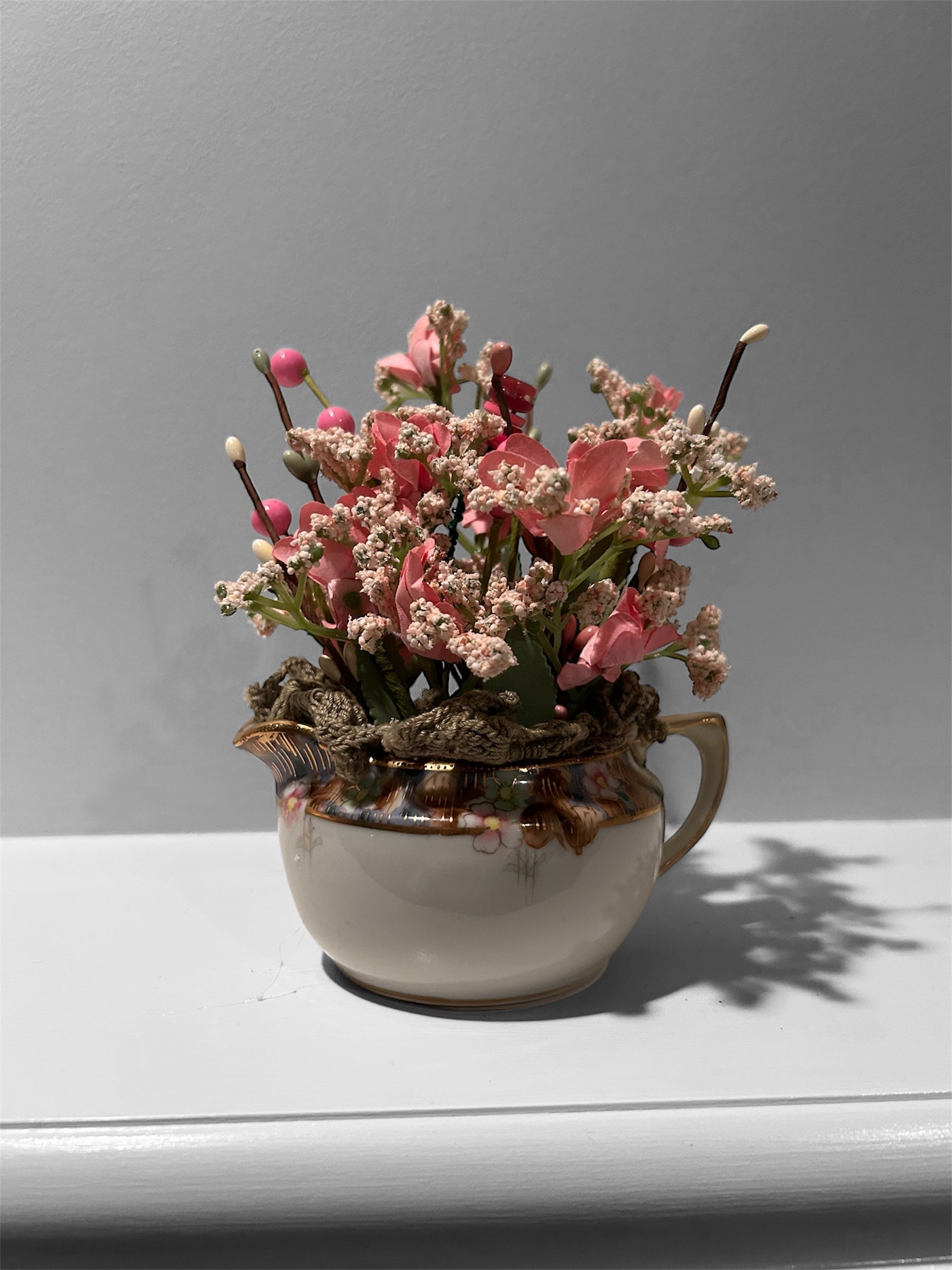 Pink flowers in white/gold creamer arrangement - green doily