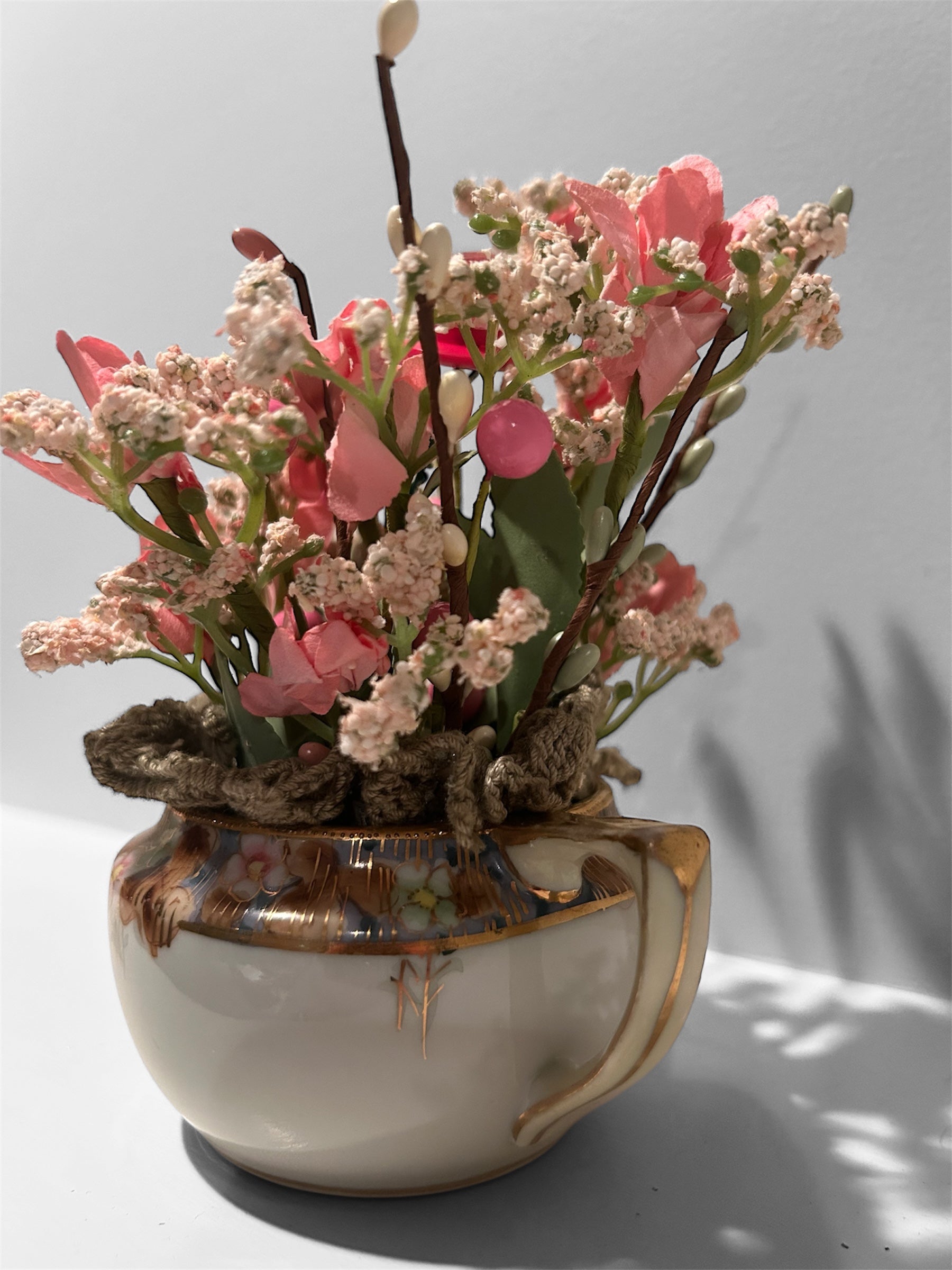 Pink flowers in white/gold creamer arrangement - green doily