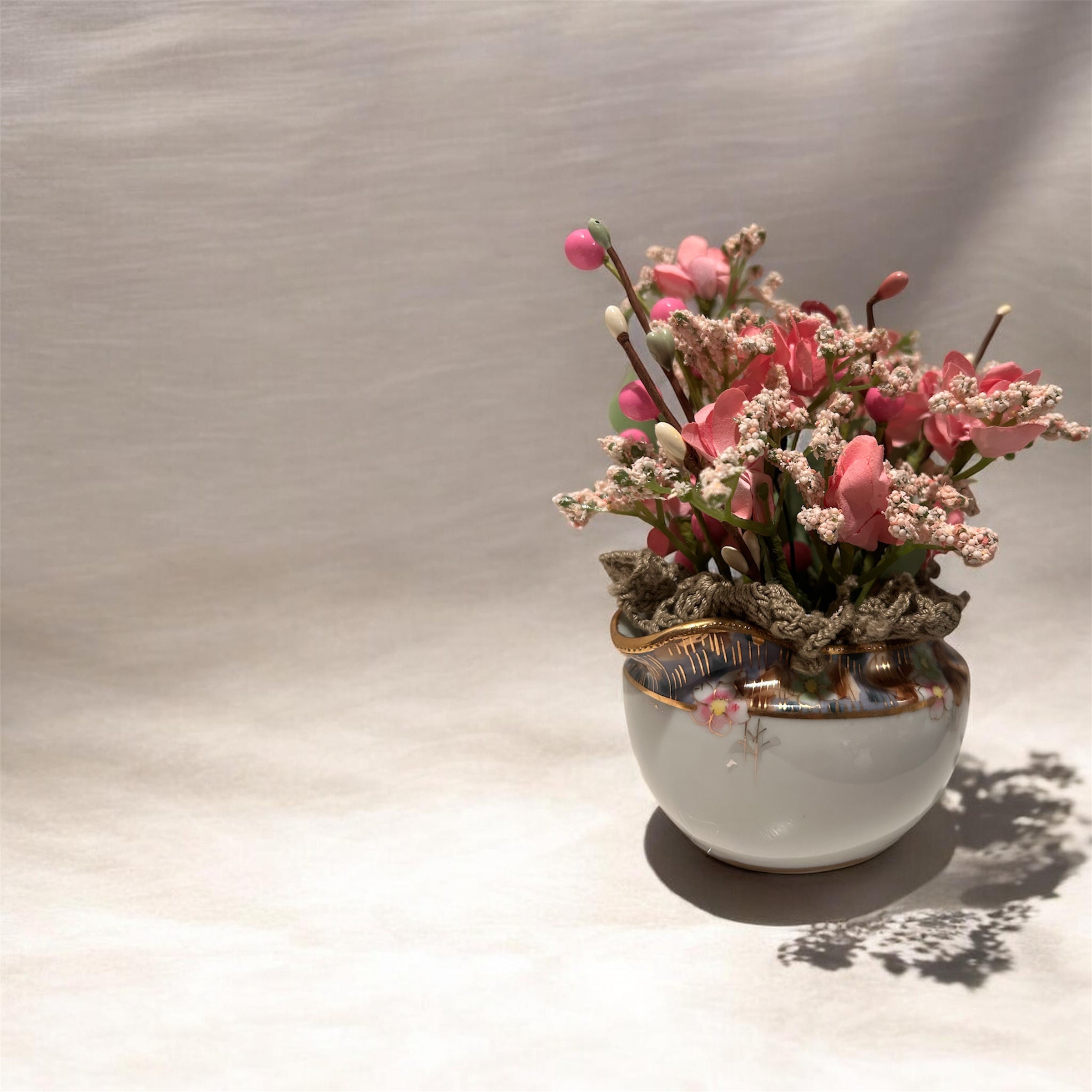 Pink flowers in white/gold creamer arrangement - green doily